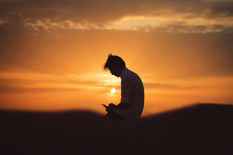 A person using their phone at a sunset time